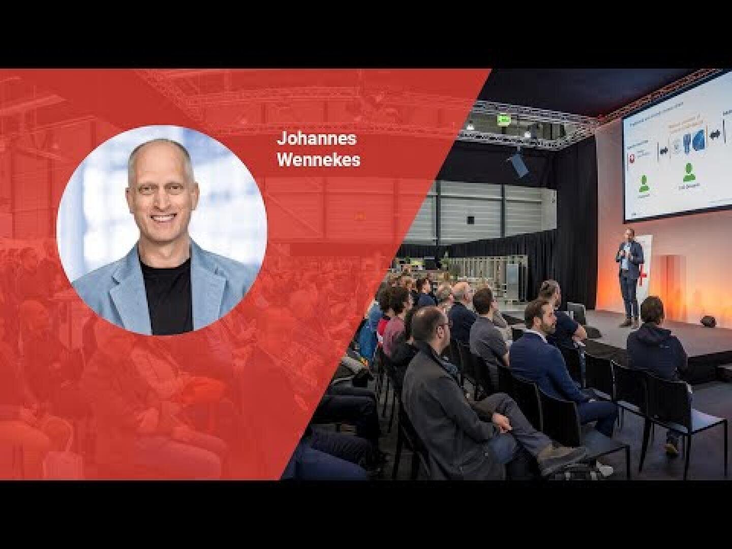 Un orateur, identifié comme Johannes Wennekes, s'exprime sur scène devant un public dans un grand hall. Une photo de lui et son nom apparaissent dans une superposition rouge sur le côté gauche de l'image.