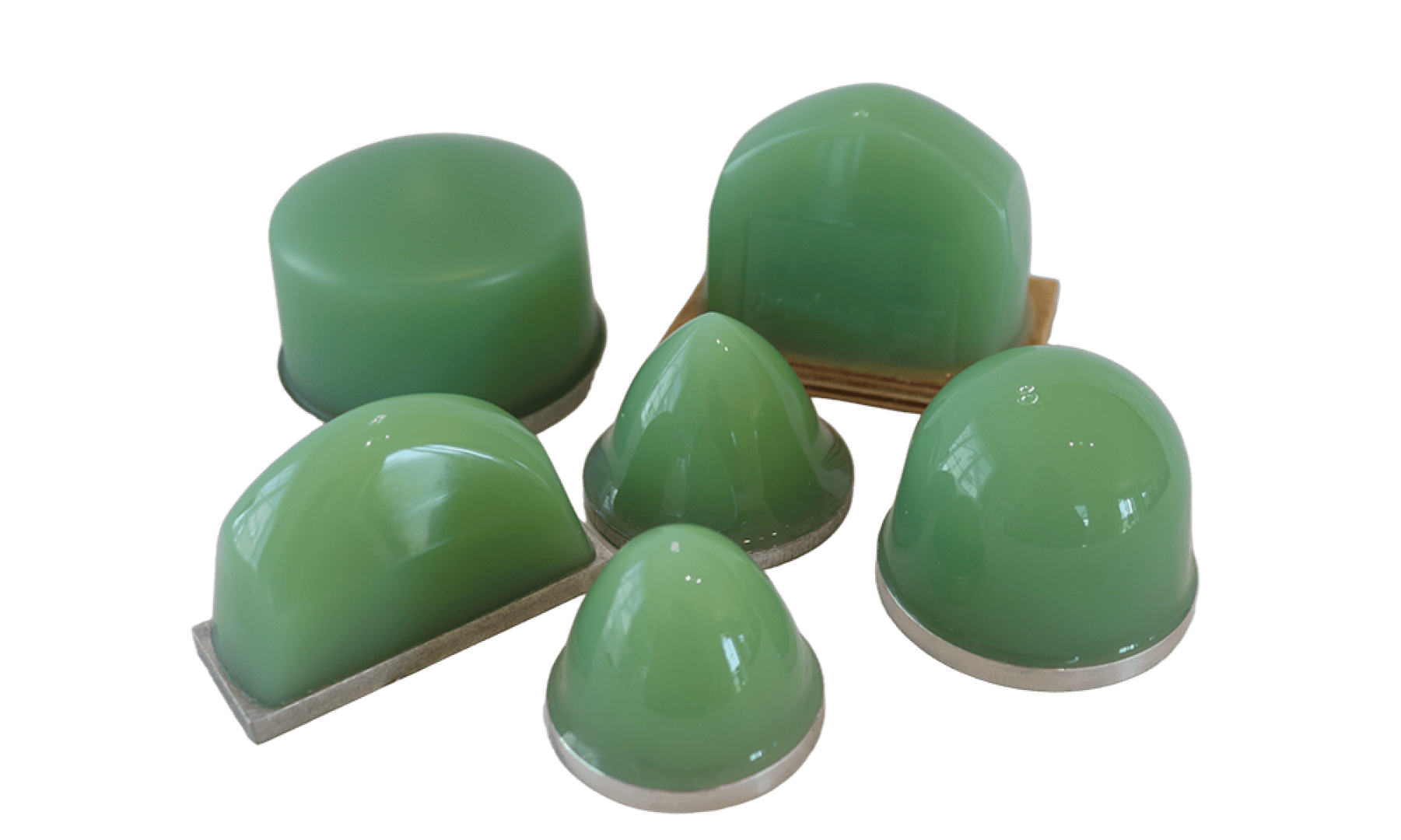 Six pierres à polir ou à aiguiser vertes, en forme de dôme, de tailles et de formes différentes, disposées sur un fond blanc. Certaines ont une base plate, tandis que d'autres sont montées sur des plaques de métal.