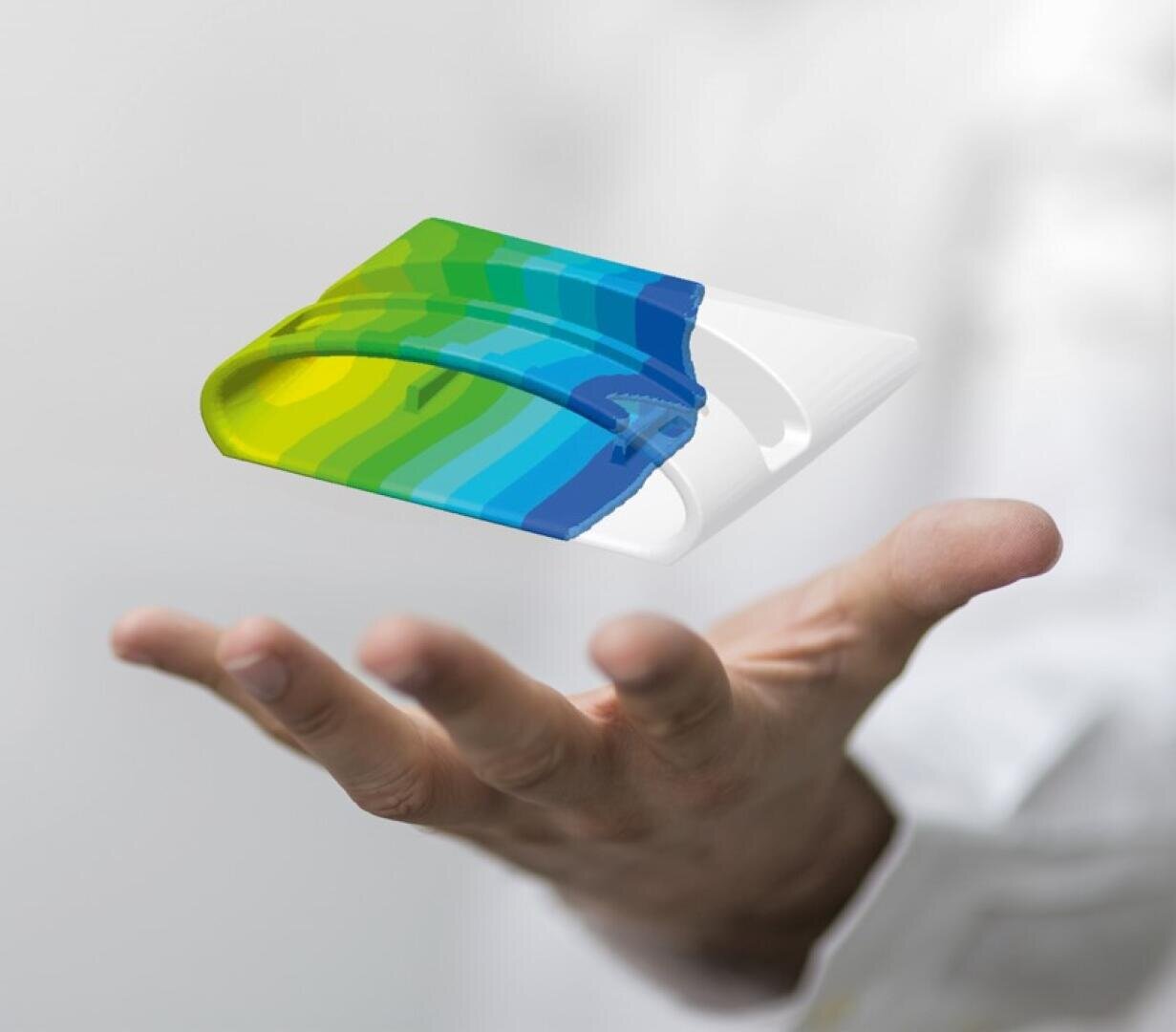 Die ausgestreckte Hand einer Person hält ein transparentes, gebogenes Objekt mit blauen, grünen und gelben Farbverläufen, das über der Handfläche vor einem unscharfen, hellen Hintergrund zu schweben scheint.