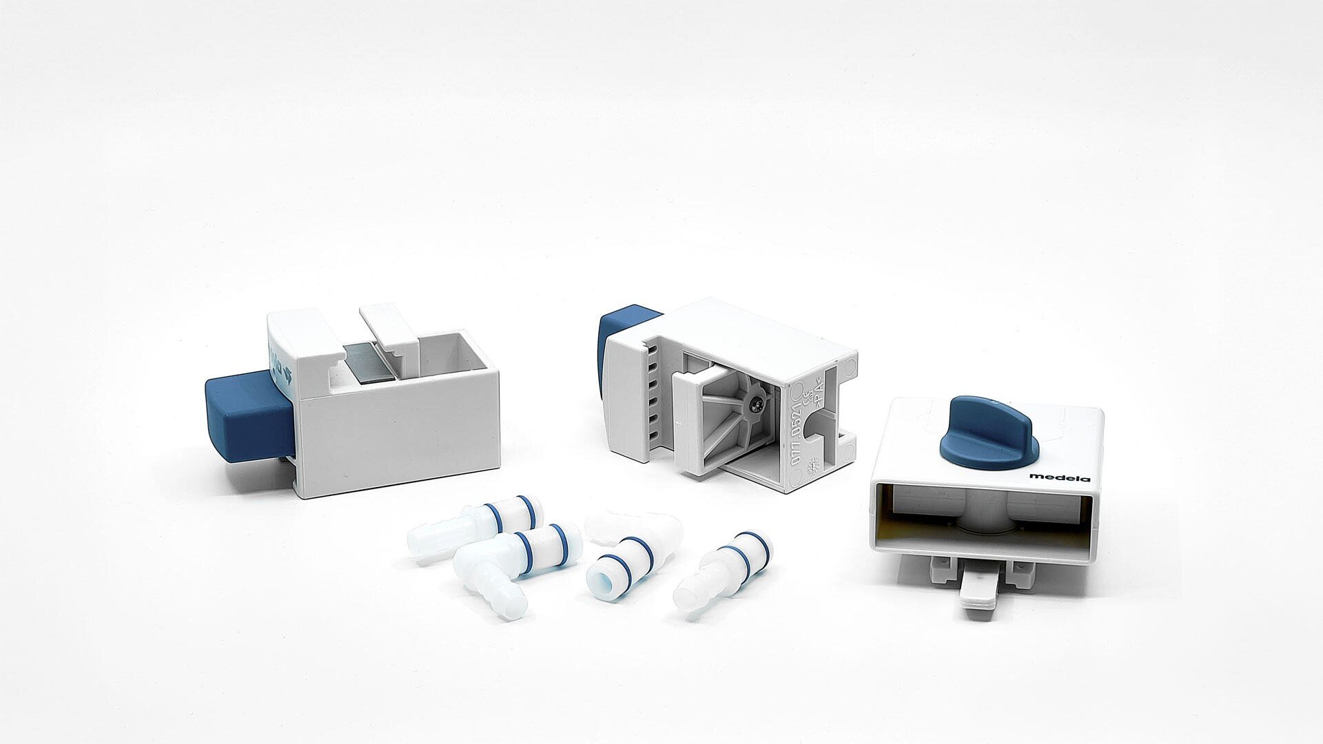 Trois dispositifs en plastique blanc et bleu avec des boutons et des ouvertures sont présentés sur une surface blanche, à côté de cinq petits connecteurs cylindriques blancs et bleus.