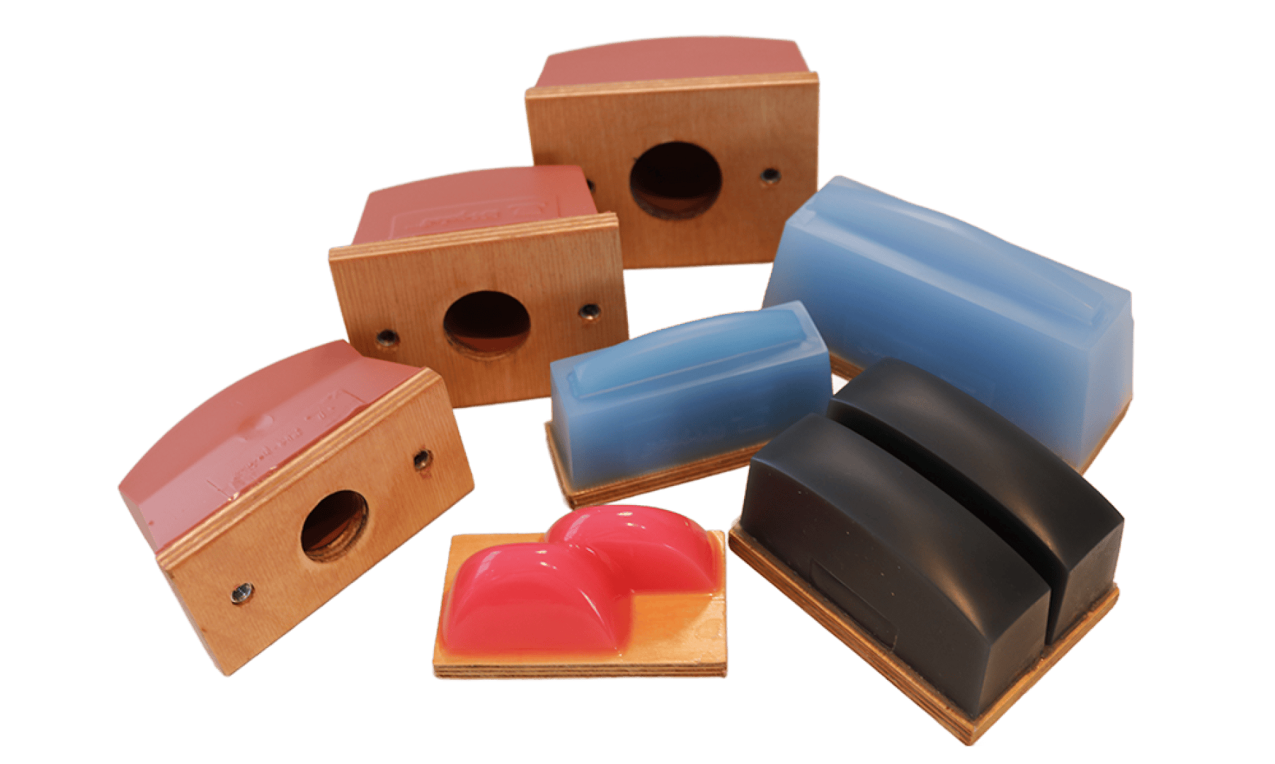 Un groupe de blocs de ponçage colorés fabriqués dans différents matériaux, notamment en caoutchouc ou en plastique rouge, bleu et noir, chacun monté sur une base en bois et posé sur un fond blanc.