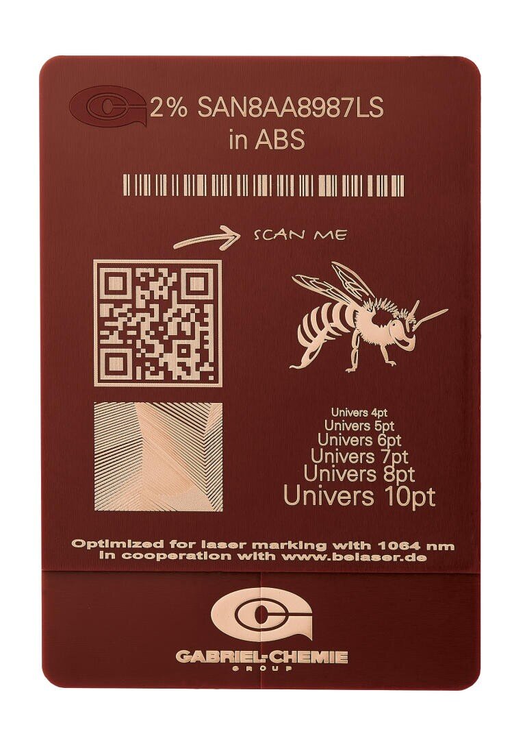 Ein rötlich-braunes Kunststoffmuster mit Lasermarkierungen, darunter ein QR-Code, eine Bienenillustration, Mustertext in verschiedenen Schriftarten und Größen sowie das Logo der Gabriel-Chemie Group. Der Text lautet außerdem 2% SAN8AA8987LS in ABS.