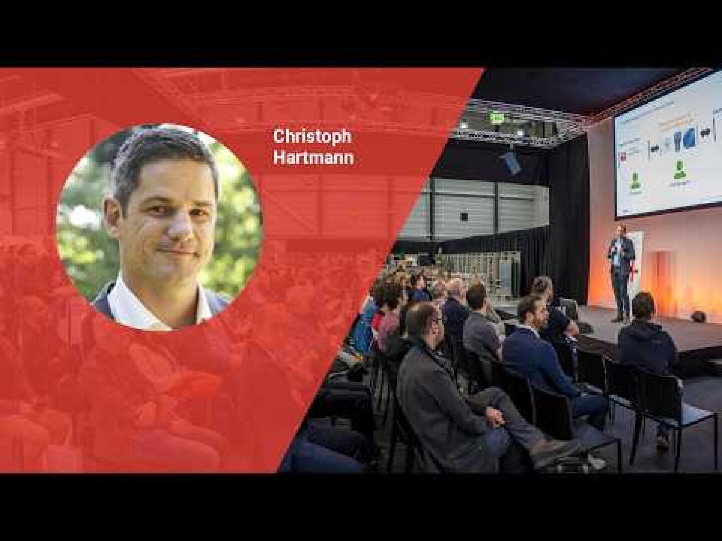 Ein Mann namens Christoph Hartmann ist in einem Porträt auf der linken Seite abgebildet. Rechts steht er auf der Bühne und hält eine Präsentation vor einem Publikum, das in einem modernen Veranstaltungsraum sitzt.