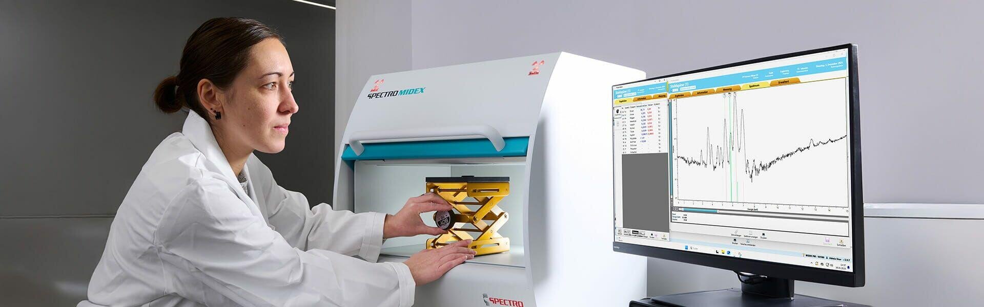 Une femme en blouse de laboratoire utilise un équipement scientifique à côté d'un ordinateur sur lequel s'affiche un graphique présentant une analyse de données.