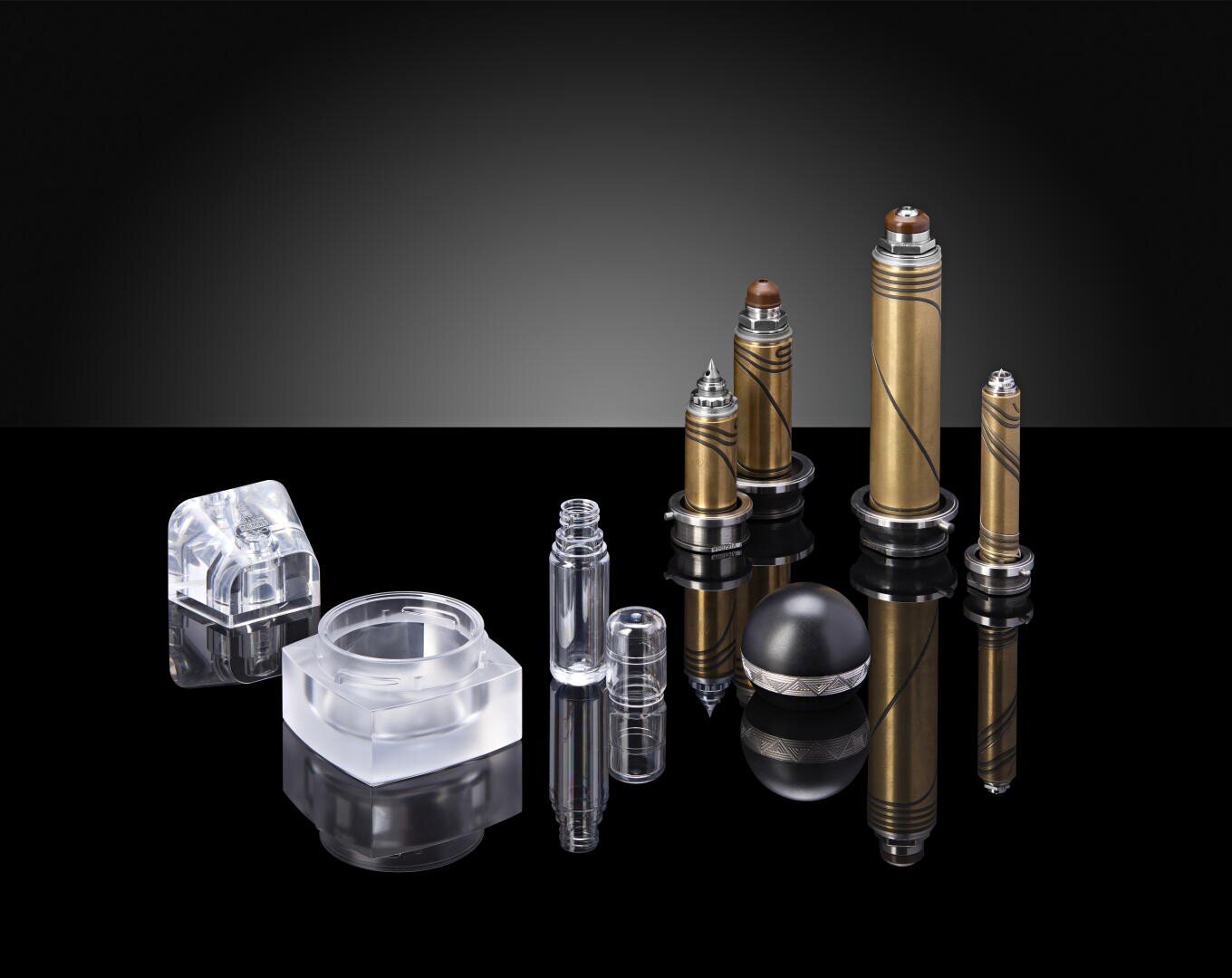 Eine Reihe von metallischen und transparenten Komponenten, darunter zylindrische Stäbe, sechseckige und runde Formen sowie eine Kugel, sind auf einer glänzend schwarzen, reflektierenden Oberfläche vor einem dunklen Hintergrund mit Farbverlauf angeordnet.