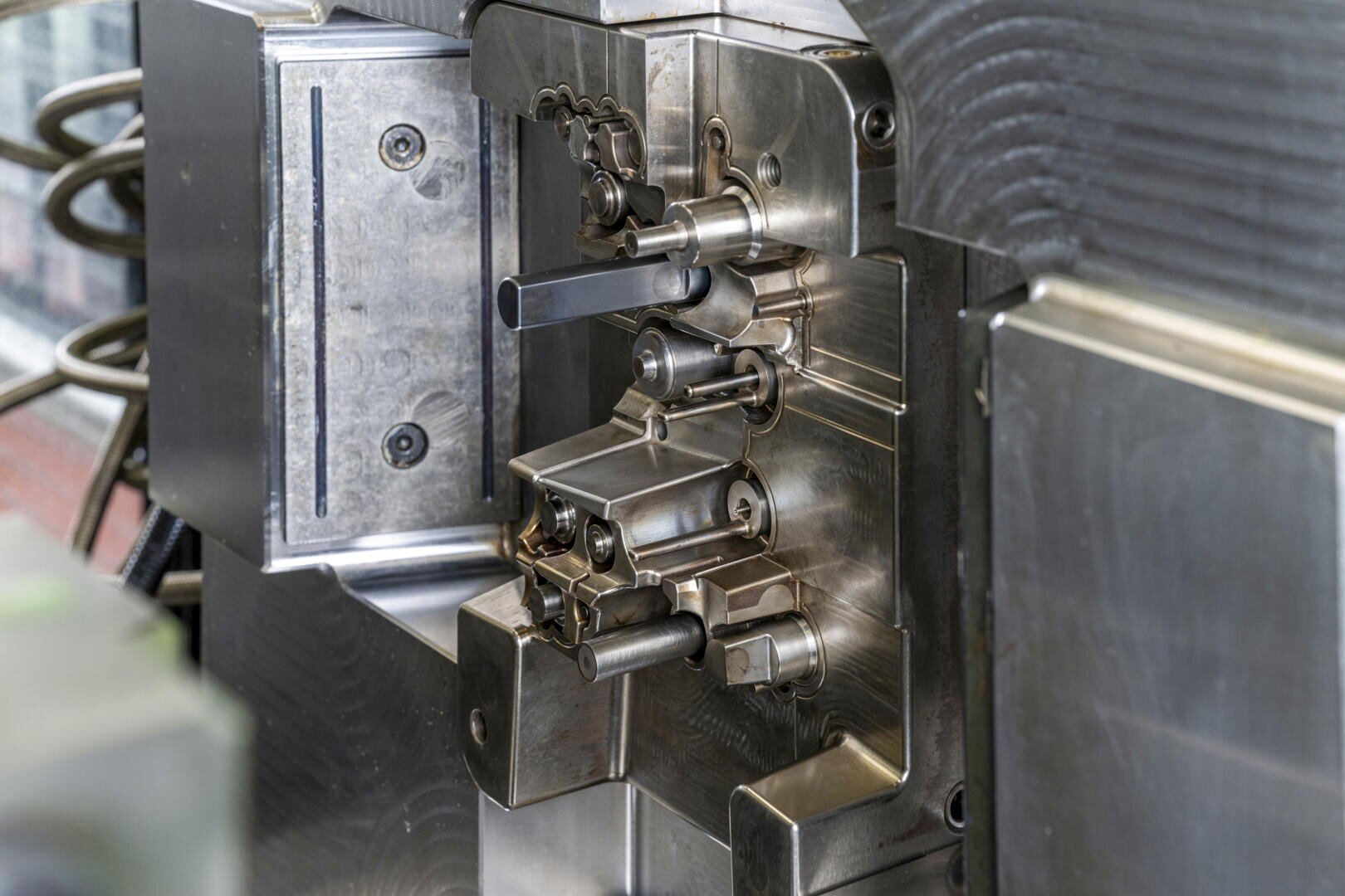 Nahaufnahme eines Präzisionswerkzeugs aus Metall mit verschiedenen Hebeln, Stangen und Komponenten, die in der industriellen Fertigung oder bei Spritzgussverfahren verwendet werden.