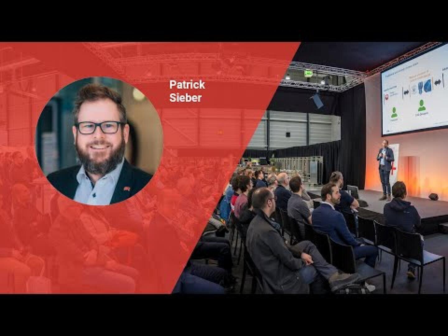 Ein Konferenzredner steht auf der Bühne und präsentiert dem Publikum Folien. Auf der linken Seite zeigt ein rotes Overlay das Kopfbild eines lächelnden Mannes mit Brille und der Aufschrift Patrick Sieber.