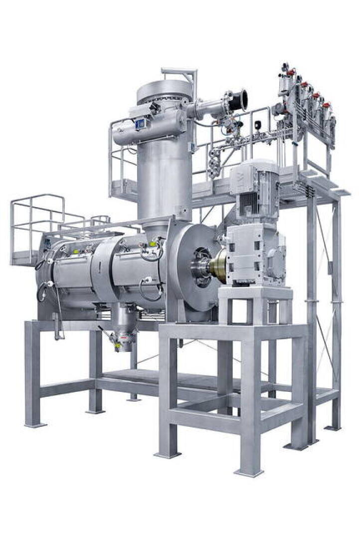 Eine große, industrielle Edelstahlbearbeitungsmaschine mit mehreren zylindrischen und rechteckigen Bauteilen, Rohren, Ventilen und Schalttafeln, die auf einem stabilen Metallrahmen montiert sind.