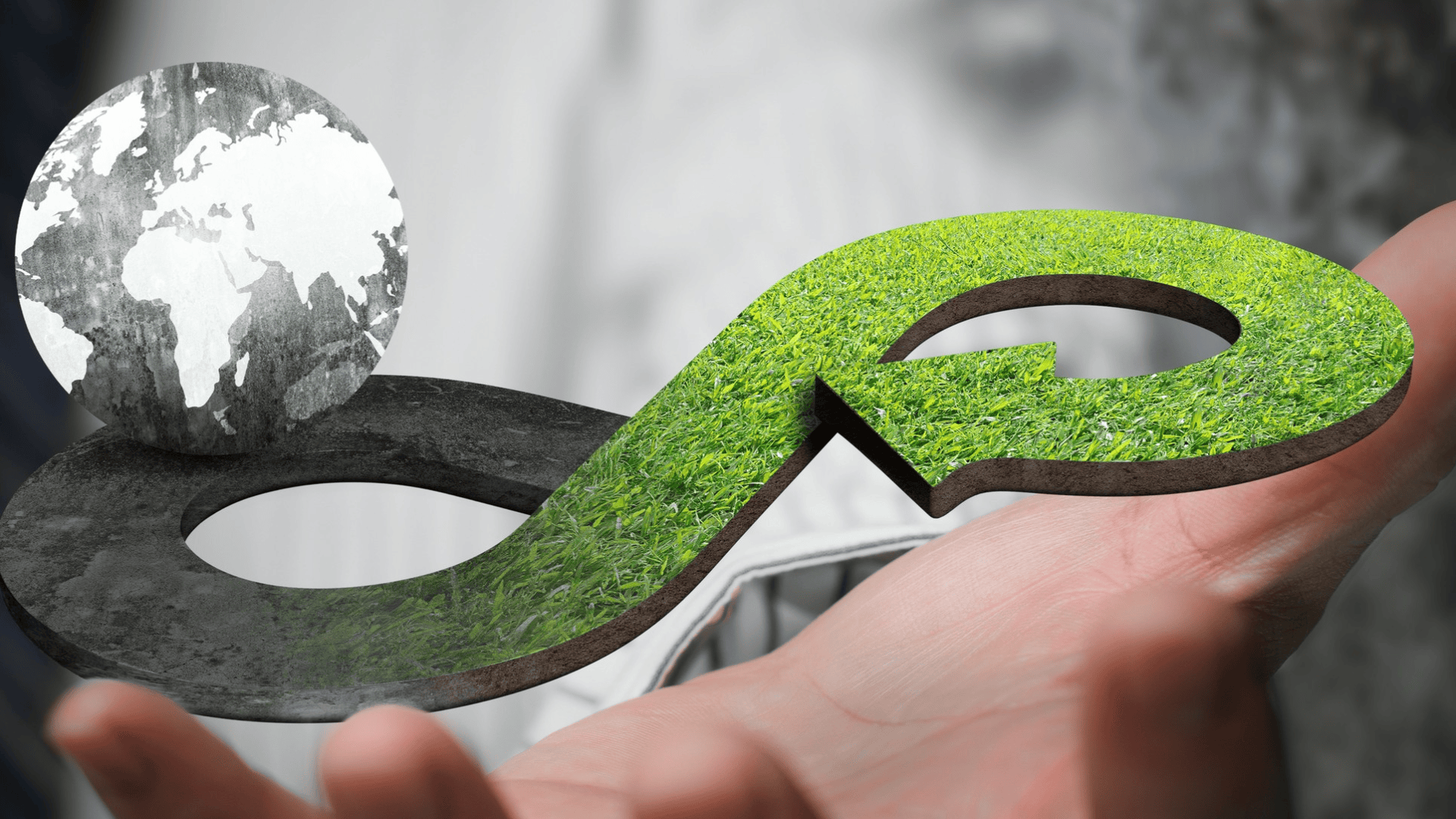 Une main tient un symbole circulaire de l'infini, à moitié recouvert d'herbe verte et à moitié de pierre, à côté d'un petit globe qui symbolise la durabilité et l'économie circulaire.