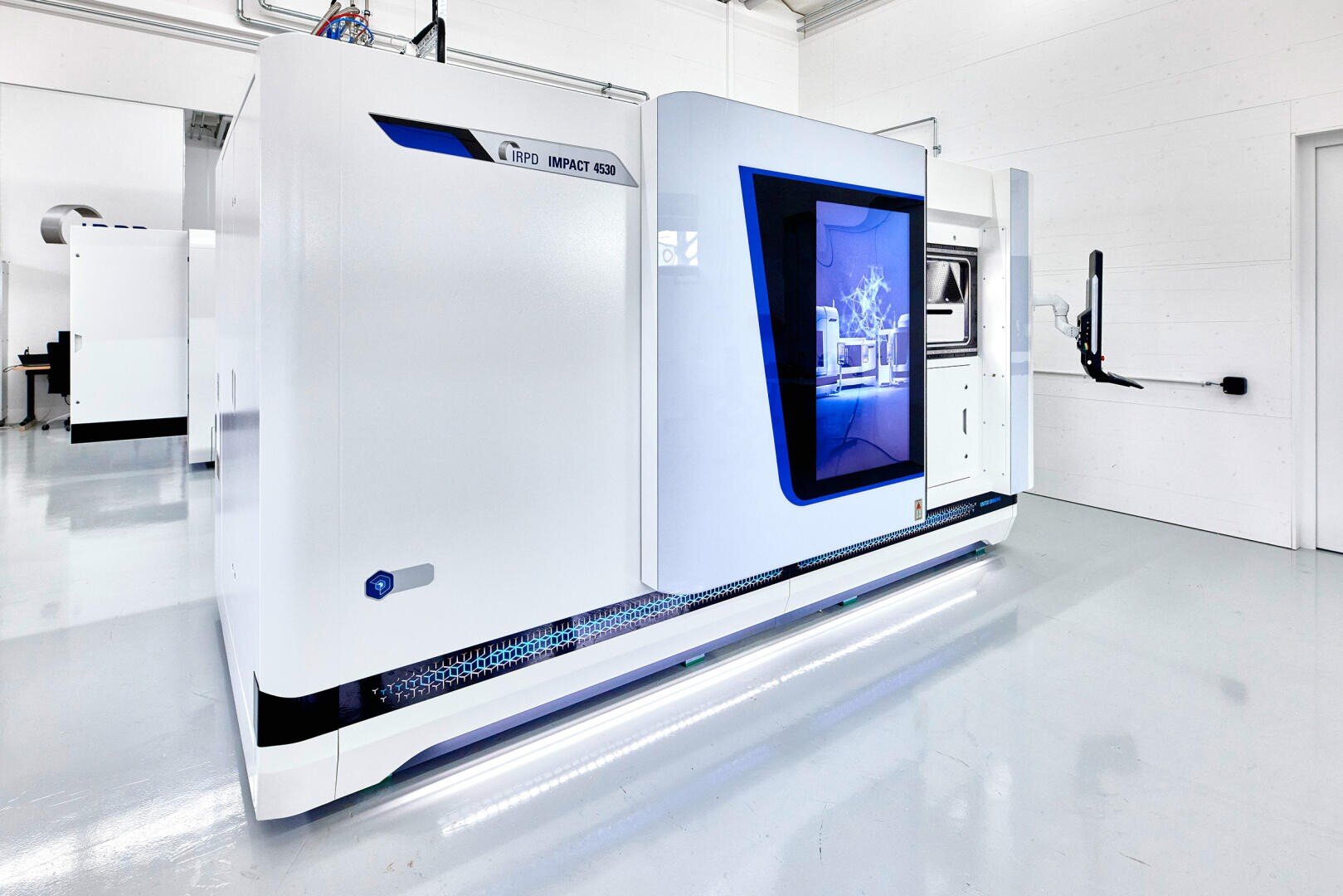 Ein großer, moderner 3D-Industriedrucker mit einem eleganten weiß-blauen Äußeren steht in einem sauberen, hellen Raum mit glänzenden Böden und weißen Wänden. Auf einem Bildschirm wird eine digitale Grafik an der Seite des Geräts angezeigt.