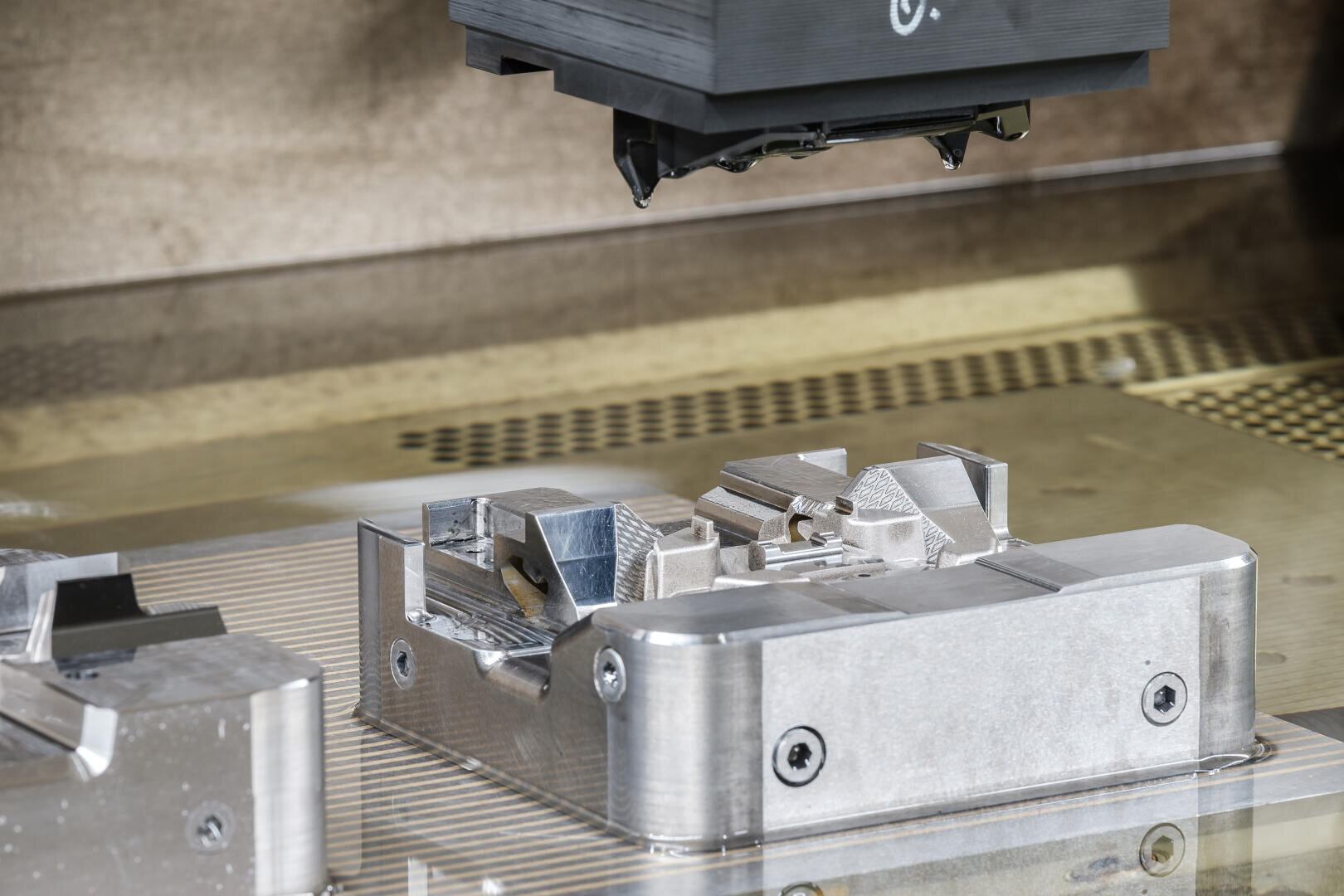 Gros plan d'une pièce de machine métallique usinée par une machine CNC de précision dans un environnement industriel, avec des rainures et des structures détaillées sur la surface du métal.