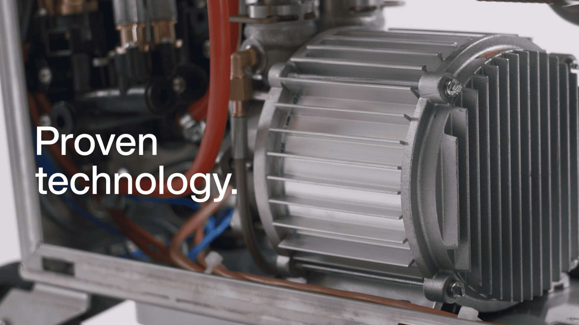 Nahaufnahme eines metallischen Maschinenteils mit sichtbaren Kabeln und Röhren; links steht in weißer Schrift "Bewährte Technologie".