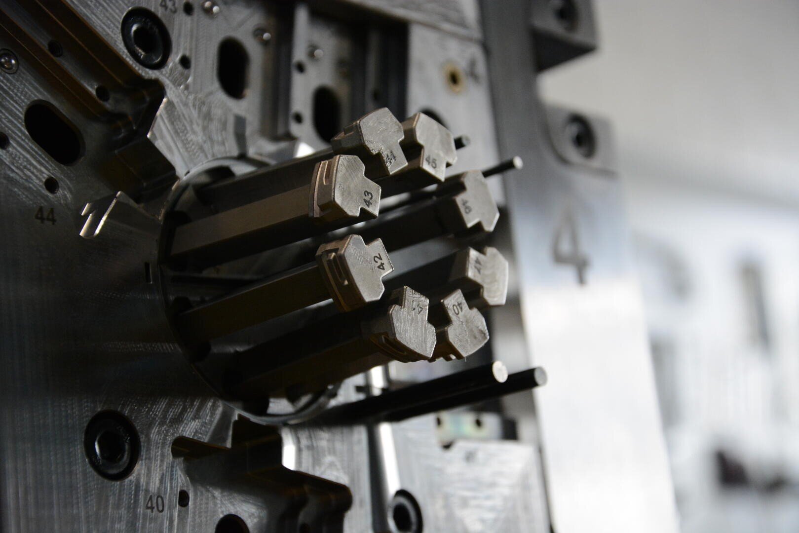 Gros plan d'une machine industrielle en métal avec des tiges métalliques rectangulaires numérotées s'étendant à partir d'une base circulaire, caractérisée par une ingénierie précise et des détails mécaniques complexes.