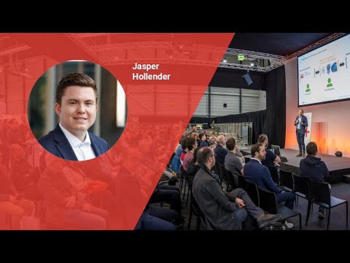 Ein Geschäftsseminar mit einem Mann, der auf der Bühne vor einem sitzenden Publikum spricht. Auf der linken Seite ist ein Kopfbild von Jasper Hollender im Anzug eingeblendet, neben dem sein Name steht.
