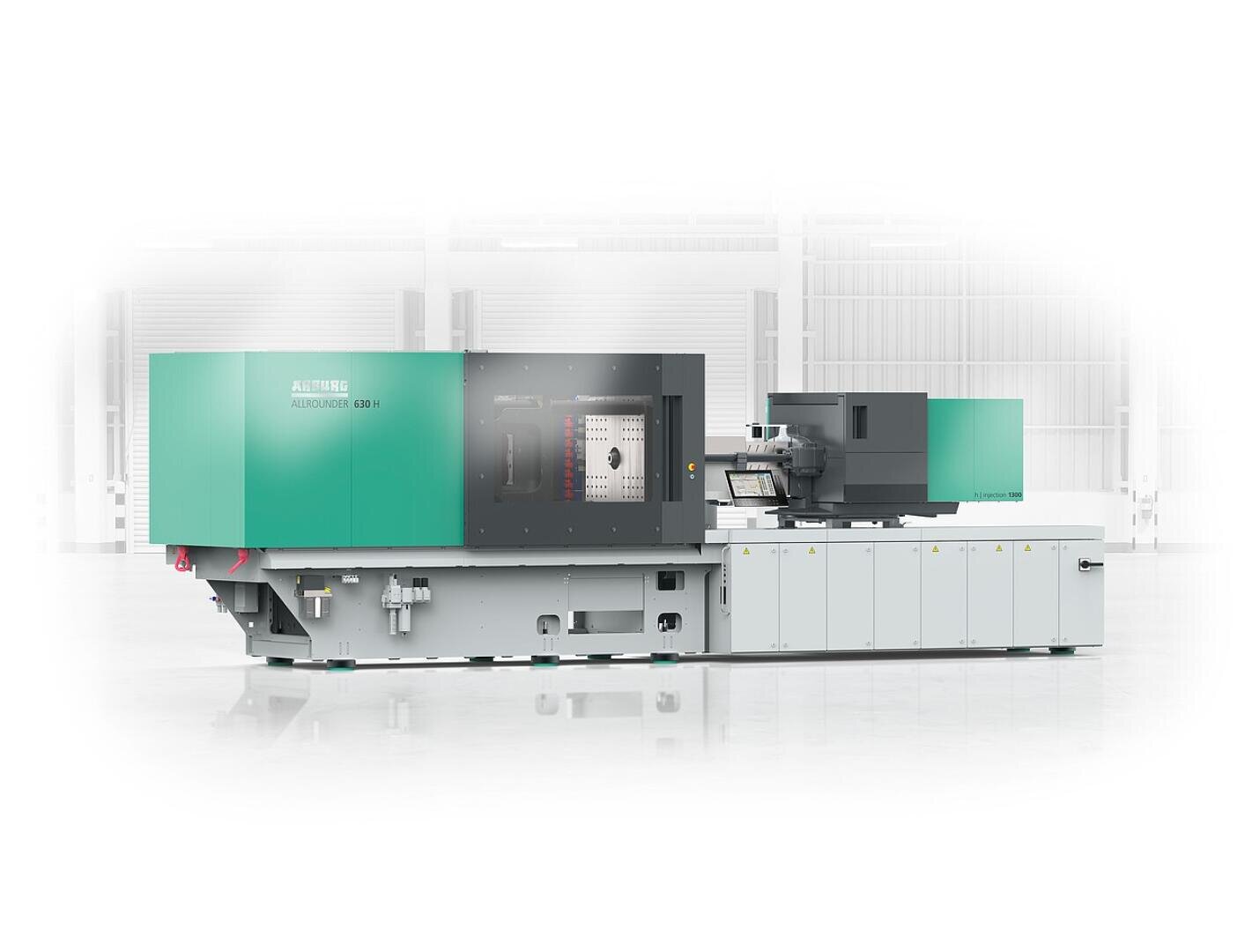 Eine große, moderne, grün-graue industrielle Spritzgussmaschine steht in einer hellen, geräumigen und sauberen Fabrikumgebung.