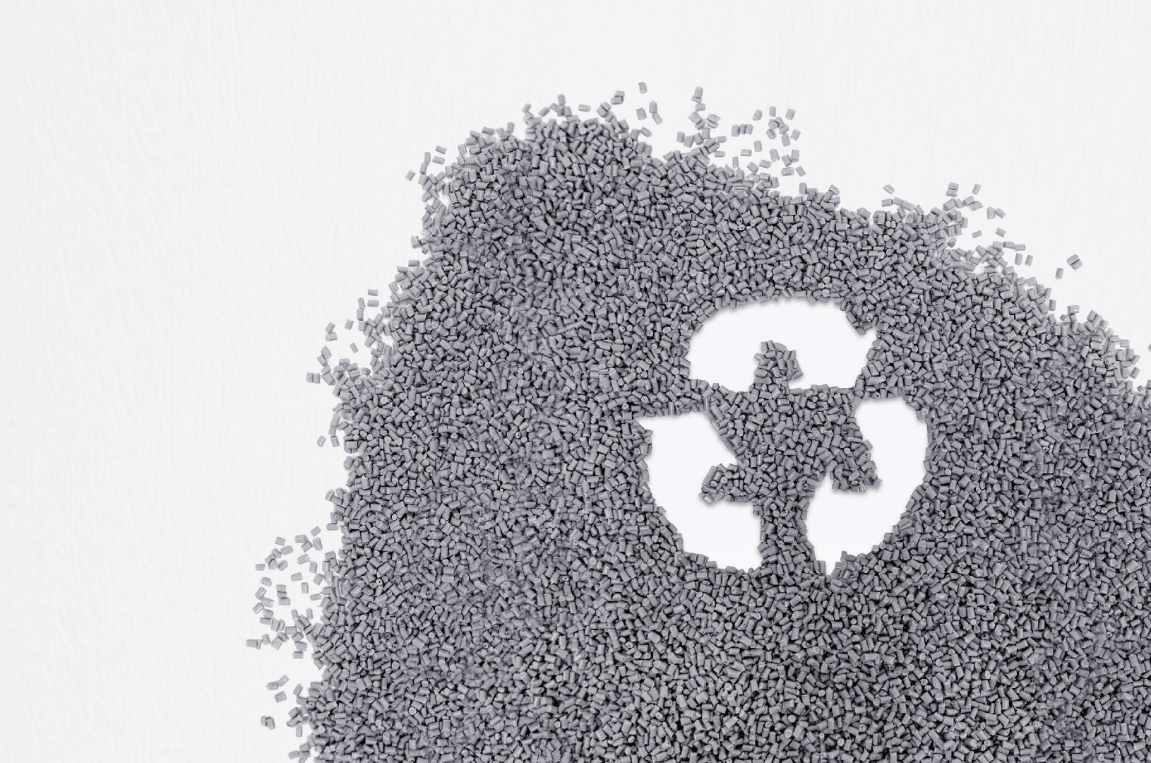 Des petites boules de plastique gris éparpillées sur une surface blanche, avec un symbole de recyclage visible à l'endroit où les boules ont été enlevées et qui représente le recyclage et la durabilité.