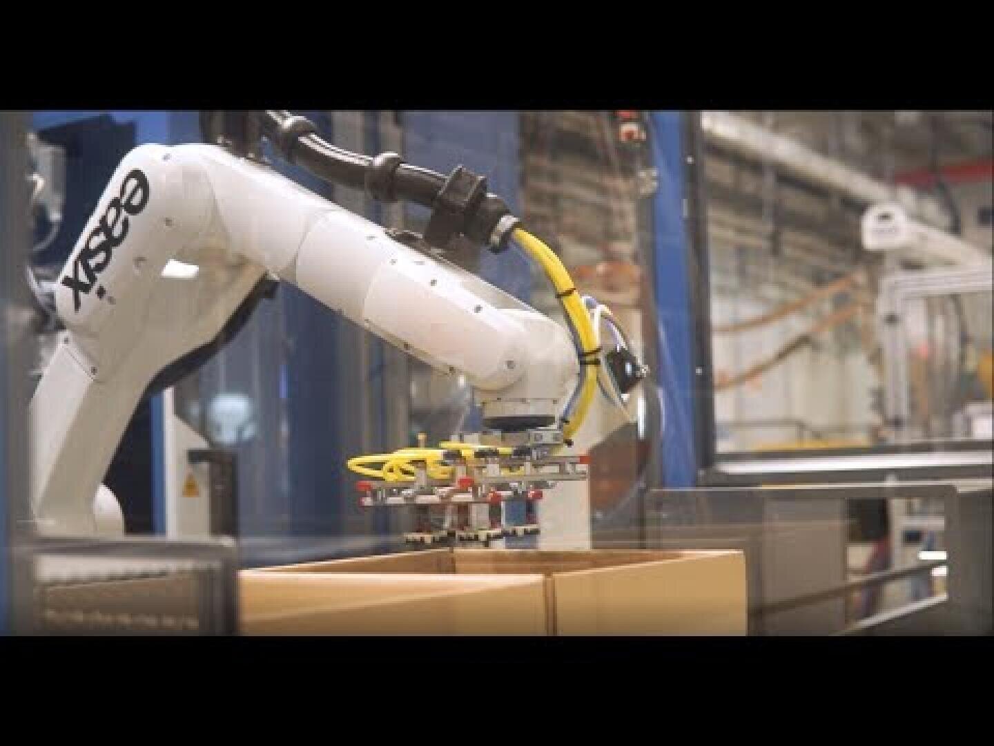 Ein Roboterarm der Marke ABB platziert oder nimmt Kartons in einer Industrie- oder Lagerumgebung auf und verdeutlicht die Automatisierung von Verpackungs- oder Fertigungsprozessen.