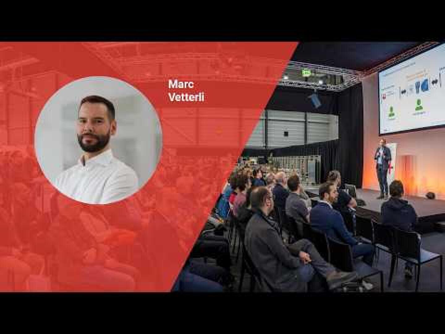 Ein Mann namens Marc Vetterli ist in einem kreisförmigen Porträt auf einem roten Overlay neben einem Foto zu sehen, auf dem er auf der Bühne zu einem in einem Konferenzsaal sitzenden Publikum spricht.