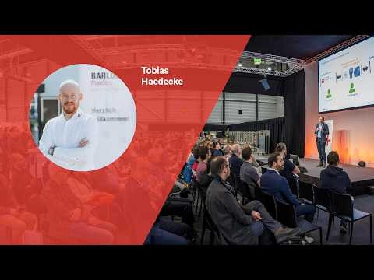Ein Mann namens Tobias Haedecke ist links auf einer roten Grafik abgebildet, während man rechts sieht, wie er auf der Bühne zu einem Publikum spricht, das in einem großen Saal sitzt, wobei hinter ihm auf einem Bildschirm eine Präsentation angezeigt wird.