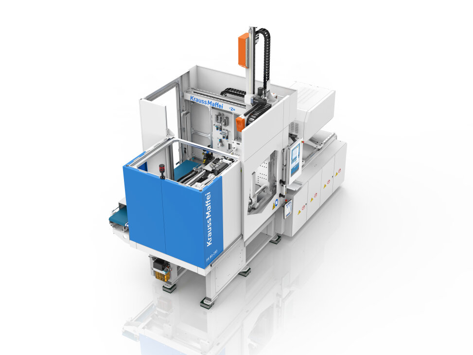 Eine große industrielle Spritzgießmaschine, hauptsächlich weiß mit blauen Paneelen mit der Aufschrift KraussMaffei, mit einem geschlossenen Arbeitsbereich, Schalttafeln und mechanischen Komponenten für die Fertigungsprozesse.