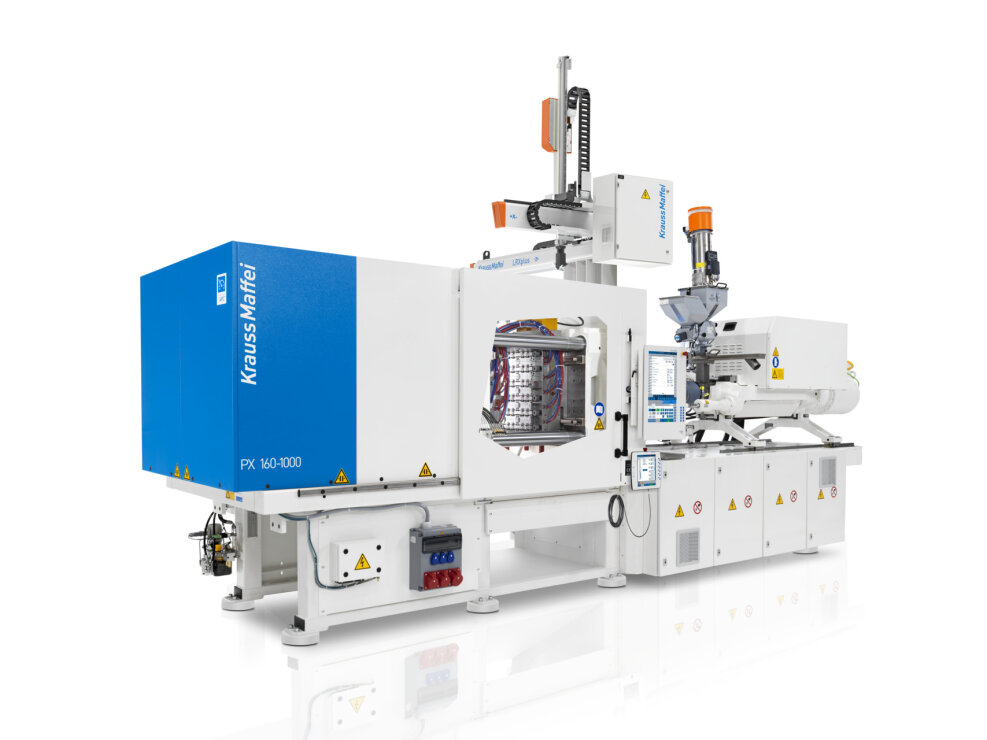 Eine große weiß-blaue Spritzgießmaschine PX 160-1000 von KraussMaffei mit Bedienfeldern, Warnschildern und sichtbaren Mechanismen für die Kunststoffherstellung.